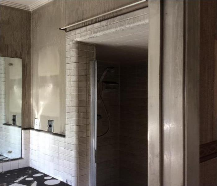 modern bathroom doorway, cream/ tan colored, corner of mirror showing