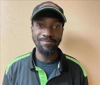 Black male in a black SERVPRO polo and a black hat