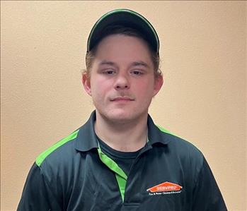male wearing SERVPRO hat and shirt standing against wall