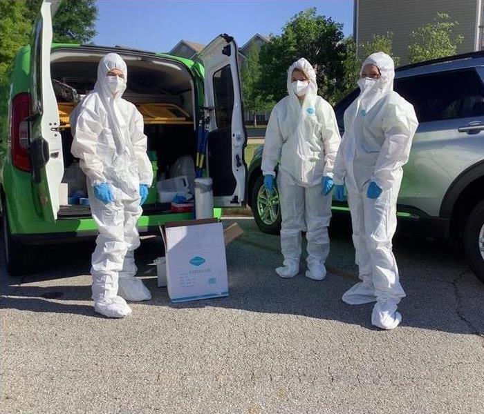 three individuals in white suits to protect them from hazard material